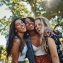 Portrait of a happy multiethnic group of smiling female friends - women laughing and having fun in the park on a sunny day